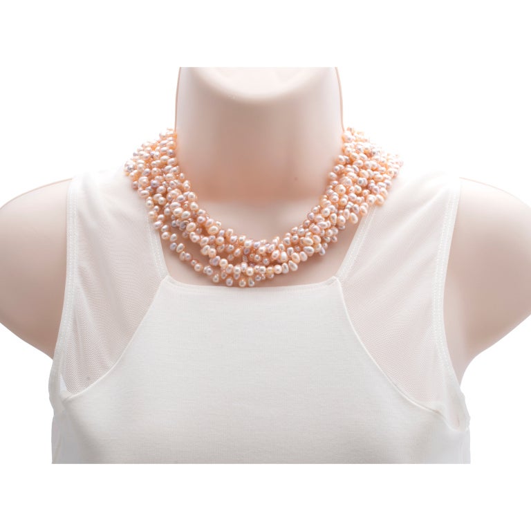 7 strand natural color undyed fresh water cultured pearl necklace. 1 1/2 inch wide loose. Shortens to 16 1/2 to 17 inches when twisted.

Approx. 749 fresh water cultured pearls, soft golden peach and plum color, egg shaped, 6.5 to 7 x 5mm, few