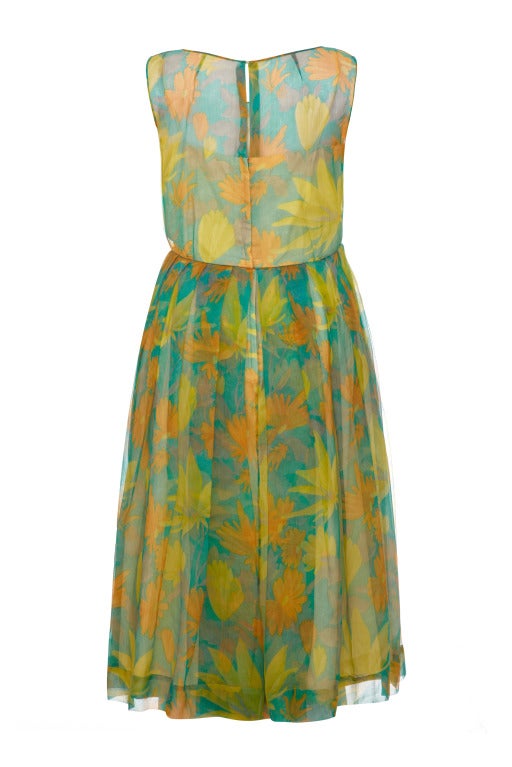 A beautiful and very summery green chiffon early 1960s dress with pretty yellow and orange floral print.  This feminine sleeveless dress is fully lined in a yellow silk lining and fastens at the back with a zip.  It is unlabelled but couture made