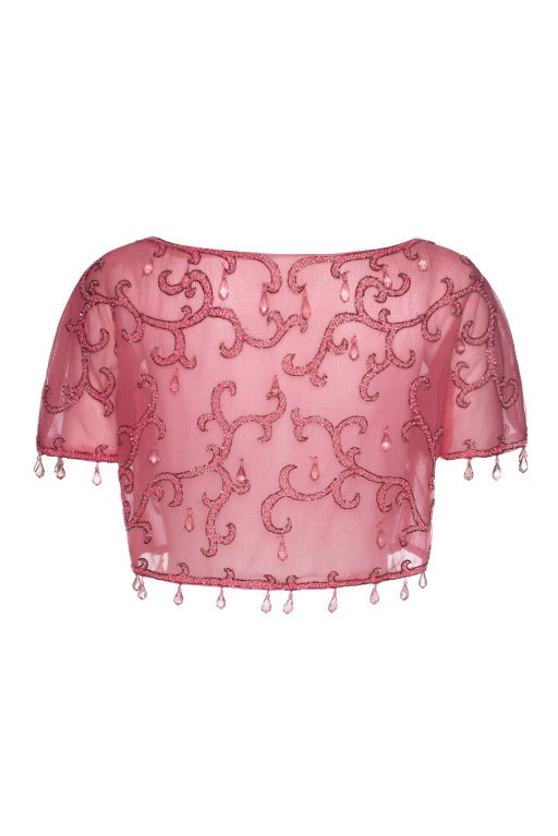 An absolutely stunning 1950’s cropped evening bolero made up of a double layer of pink silk organza with a fine mesh in between.  
This piece features a pretty swirling pattern of pink and silver beads and is edged all around with large pink
