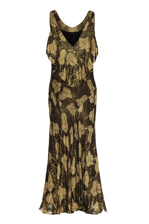 This sensational vintage 1930s full length lamé gown in a black and gold floral design is cut on the bias to create a flattering silhouette. Panelling in the skirt makes the dress fall beautifully and hangs slightly longer at the back.

There is