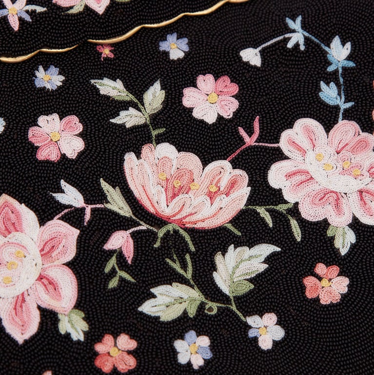 This gorgeous 40’s handbag features an intricate multi-coloured embroidered floral motif on a black beaded background. Inside, the bag is lined with black satin and has two smaller pockets on each side.