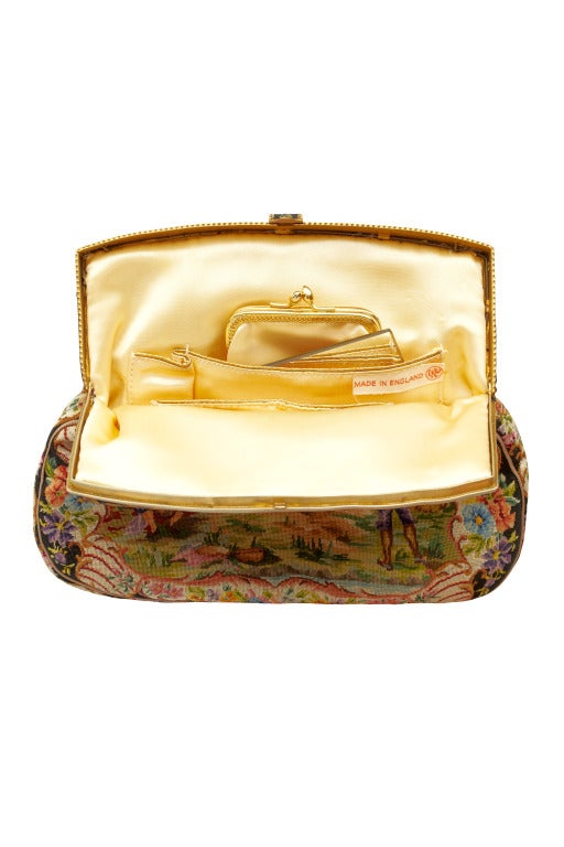 This late 1950s gilt frame petit point clutch bag depicts a wonderful medieval outdoor banquet scene.  Inside, the bag is lined with yellow satin and has two pockets containing a lipstick holder and mirror and a separate coin purse.
