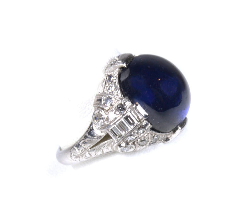 The ring contains one center oval blue star sapphire cabochon, prong-set, with measurements of 12.20 x 10.70 x 8.10 mm and an estimated weight of 11.02 cts.  The sapphire is described as intense medium-dark slightly violetish blue with a slightly