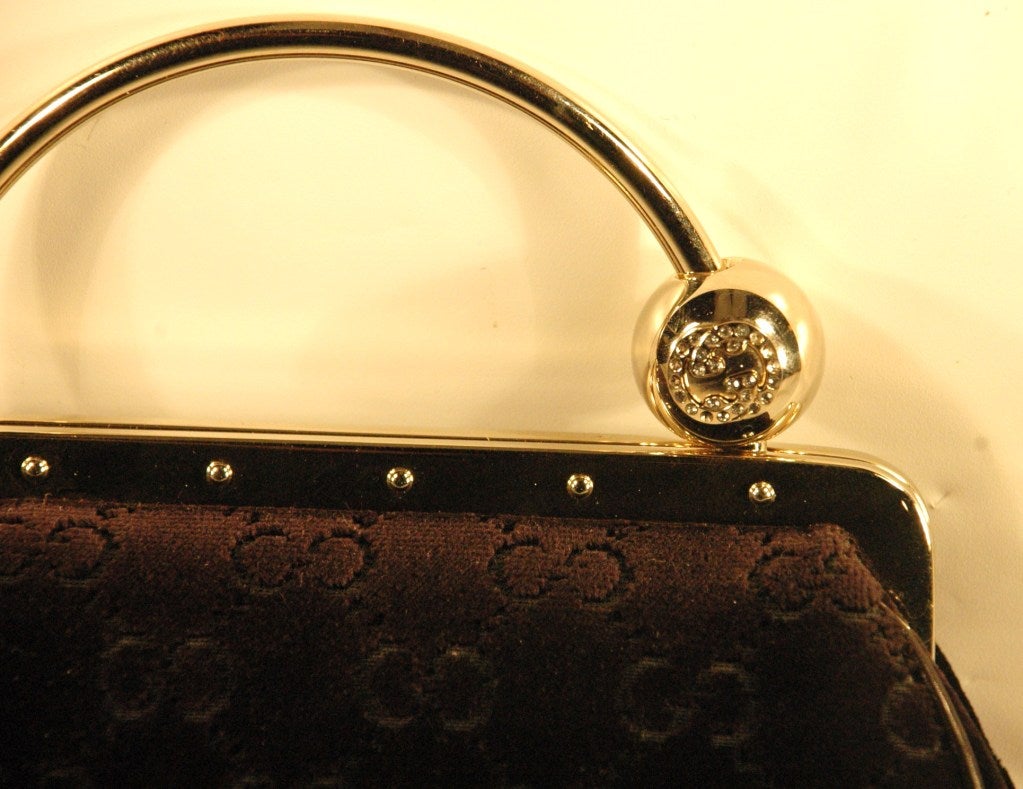 This top evening bag from Gucci is black velvet with Guccissima pattern with silver metal frame evening bag with metal handle and circular charm with swarovski crystal.  Circluar detail slides on metal handle for opening and locking closed.  SIlk