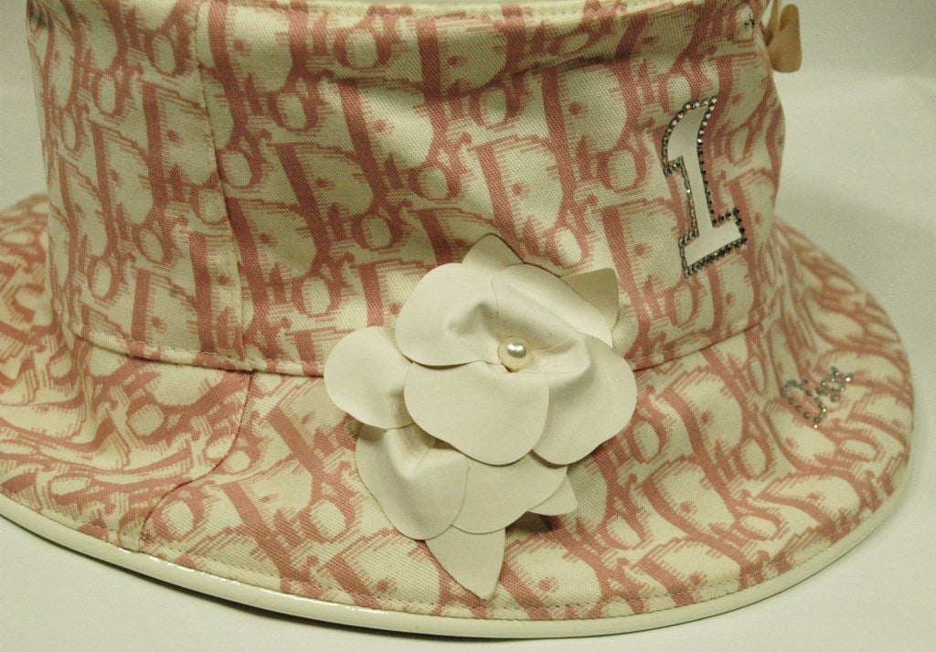 This is a beautiful Christian Dior Boutique pink & white hat with white flowers and crystal #1 and Dior logo.  Made in France sz 58
Measurements:
inner diameter 6