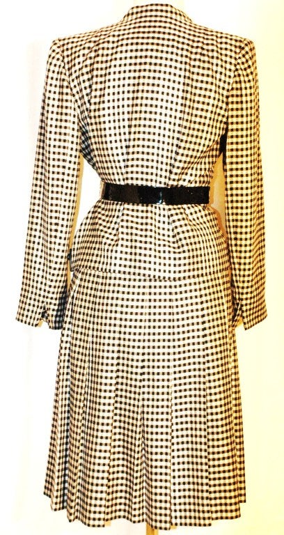 This is a vintage Pauline Trigere black and white checker jacket with woven thru built in belt loops and pleated skirt. Size 8  Made in USA of imported fabrics.  
Fully lines
Measurements:
Jacket 24