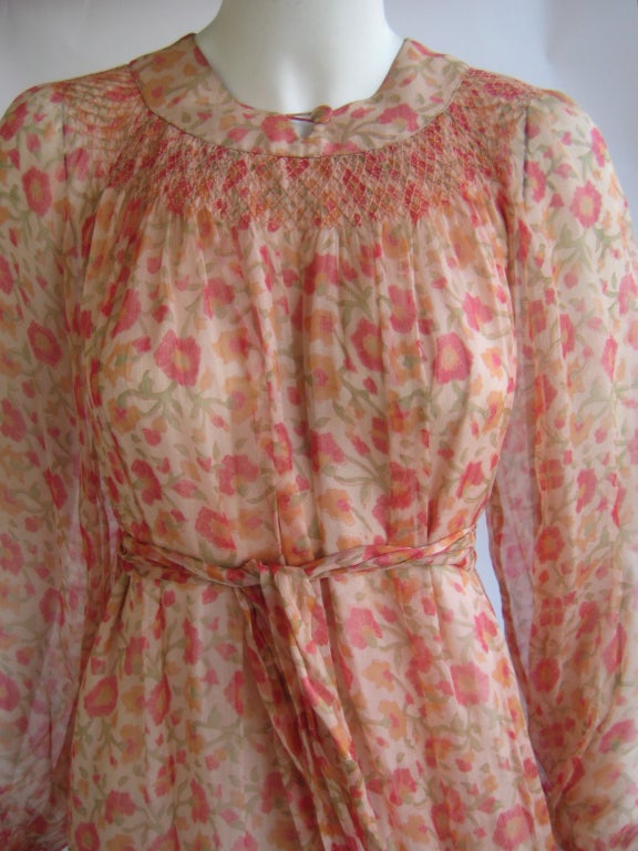 Pink floral silk chiffon
Lined in pale pink silk 
Matching sash
Smocked bodice and cuffs 
Silk covered button at front neckline closes with silk loop
3 matching buttons with silk loops at each cuff
Labeled vintage size 16 .Dress is shown on a