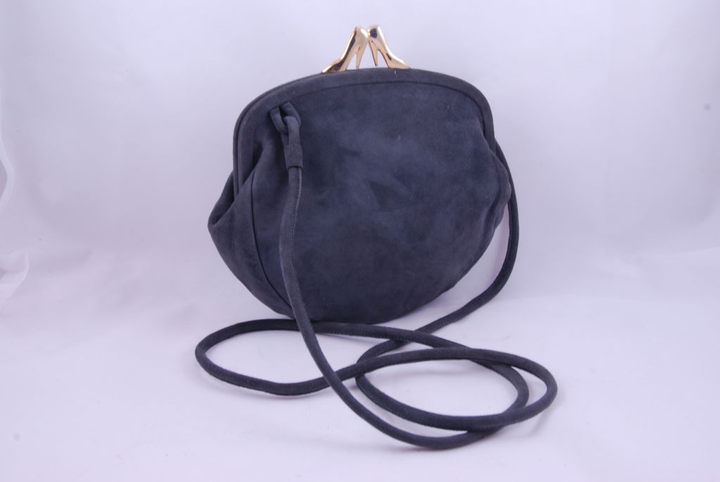 Gray suede small hand bag with charming clasp. The kiss lock clasp is gold metal in the shape of two stiletto shoes. The bag has an extra long suede strap so the bag can be worn cross body of you may shorten it by tying a knot at the top of the