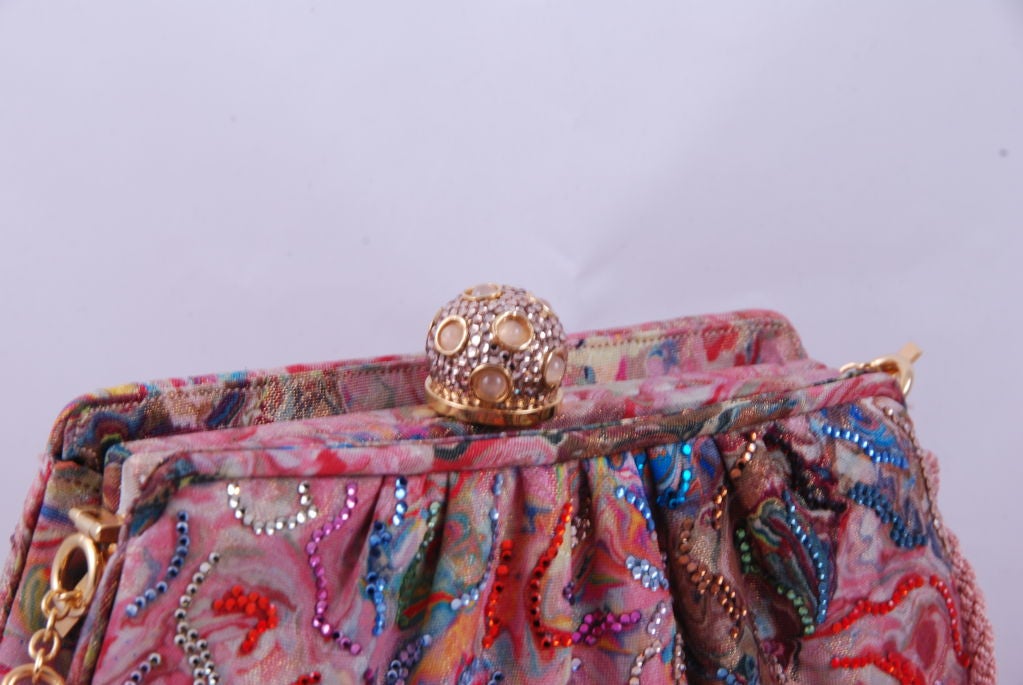 1980's fabric Judith Leiber bag which is primarily mauve but also has blues, greens, magenta, gold and yellow swirled throughout. There are also rhinestones in the above colors. The clasp is clear rhinestone with rose quartz stones. Lining is cream