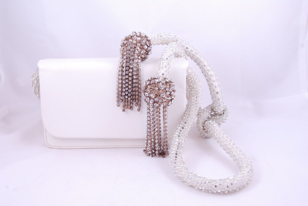 Dazzling white and rhinestone shoulder evening bag by Kenneth Jay Lane from the 1960's. When you are carrying this bag over your shoulder it looks like you are wearing a fantastic piece of jewelry. The tassels are make of metal and entirely covered