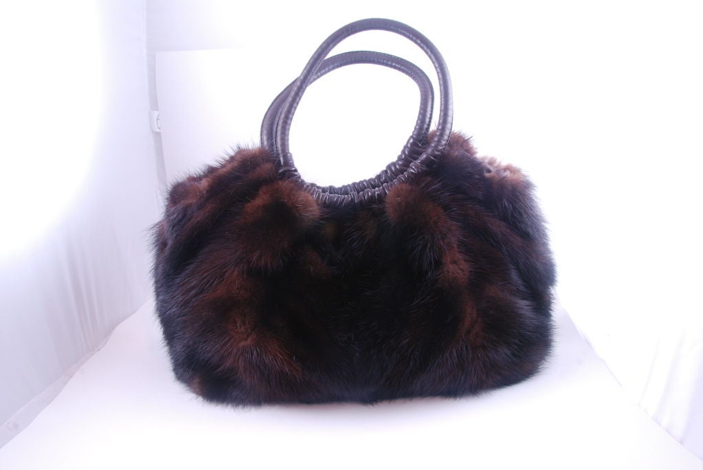 Paola del Lungo larger handbag made of deep brown mink. The long mink is formed into a chevron design on the front and back. The bottom of the bag and the handles are brown leather. The bottom has 4 silver tone feet to prevent undue wear of the