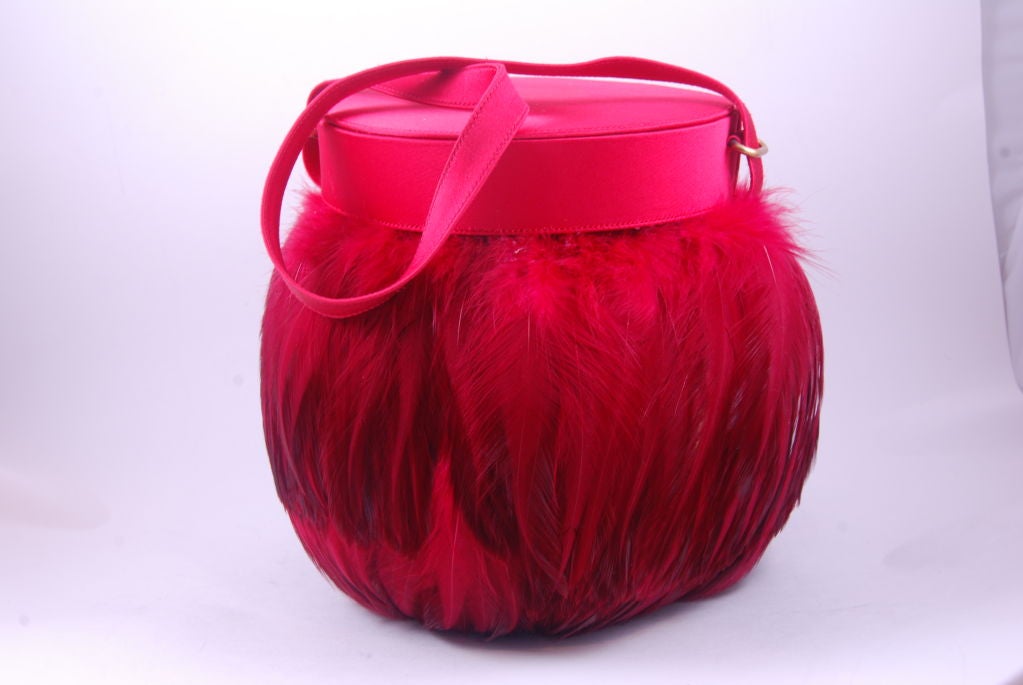 Evening bag covered in red feathers with red satin strap, lid and rim. This bag is by the French designer Renaud Pellegrino which was carried by stores such as Bergdorf Goodman. This bag was retailed by a store in South Florida called 