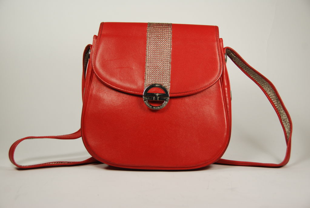 Red leather Paco Rabanne cross body or shoulder bag from the 1960's. Bag is trimmed with silver tone mesh. Inside is lined with s silver/black fabric. There is one zipper compartment inside the bag. The clasp is magnetic and works well. Strap is