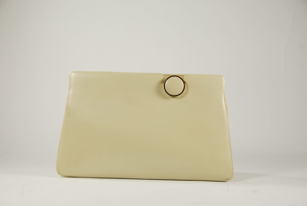 Judith Leiber smooth cream colored leather purse from the late 1960's, early 190's. Lining is a cream fabric with one zipper compartment and one slip compartment. Clasp works by lifting the leather dot on the front of the bag. Clasp works well and