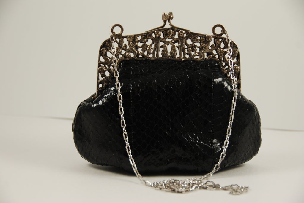 Jocomo evening bag from the 1980's with an ornate antique frame made of 800 silver. The frame is caste with putti, grape clusters and branches. The frame is probably Italian in origin. The body of the bag is black python.

Jocomo bags were made in