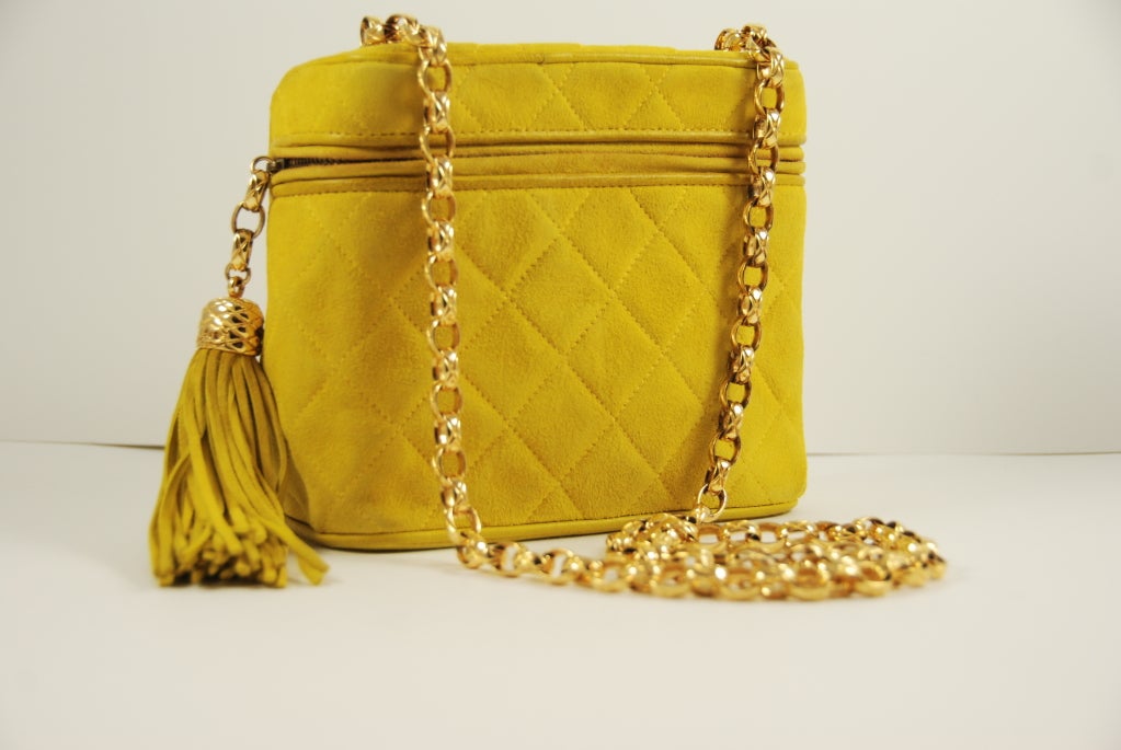 1980's - 90's yellow suede quilted binocular case type Chanel  purse with large tassel. Chain is bras and has a quilted design on it. Bag has a zipper opening and a tan leather lining.

Chain is 39
