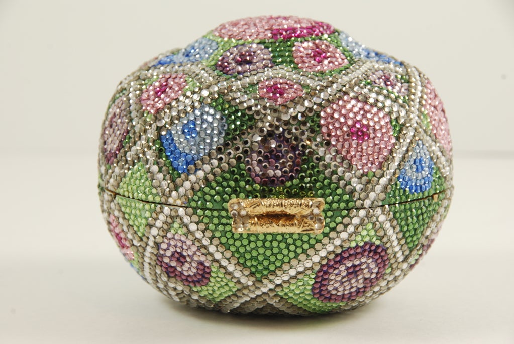 1980's Judith Leiber multi colored rhinestone encrusted minaudière. Beautiful coloration in greens, blues and pinks.

There is a gold chin that folds into e bag when not in use. The chain drop to the top of the bag is about 18