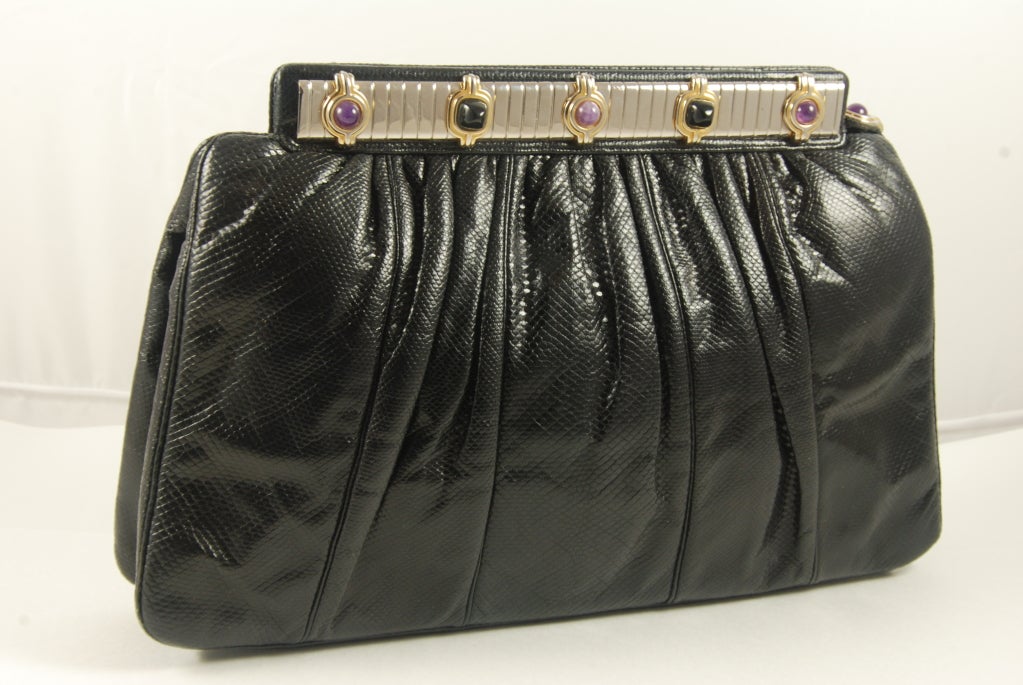 Black karung (lizard) Judith Leiber purse from the 1980's. The frame of the bag has onyx and amethyst stones on the front and back. The frame is silver and gold and the bag opens by pulling an amethyst side tab. Clasp works well. Inside is lined in