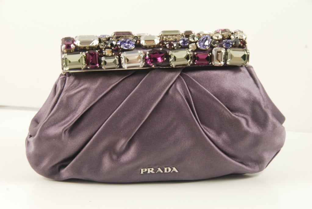 Prada lavender silk evening bag with stunning rhinestone frame. The stones are deep purple, light purple and clear and gray. They are various shapes and sizes. There is one inside slip compartment.

This bag is a clutch.