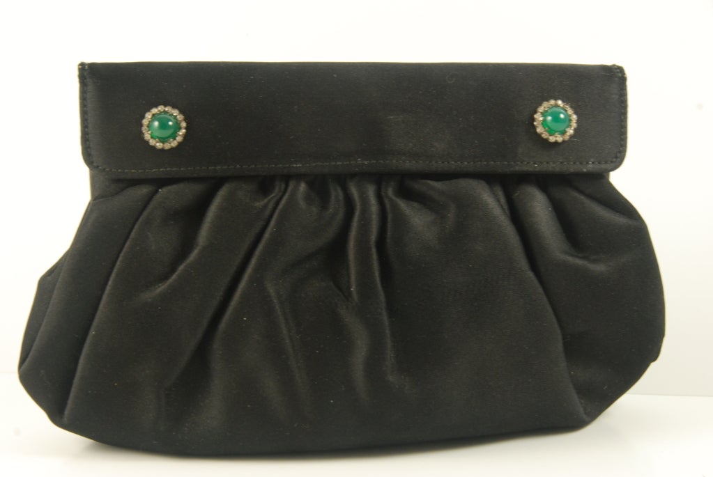 Early black satin Gucci evening bag with 2 cabochon faux emeralds surrounded by rhinestones. The lining is beige satin. I believe this bag is 1950's - 60's. This is a clutch and the only strap is on the rear.


The bag closes by two snaps that