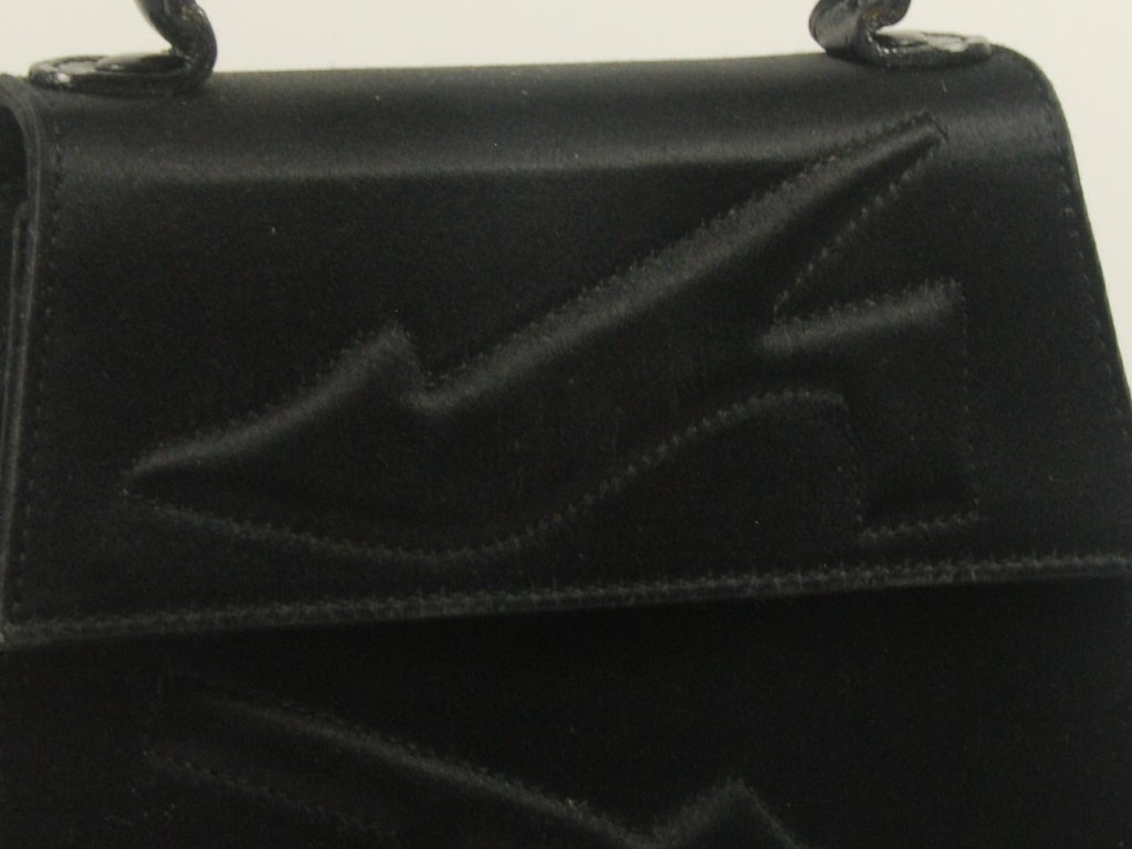 Cute black sating evening bag with a black leather handle. The front of the bag is decorated with two raised quilted shoes.

Handle measures  8.5