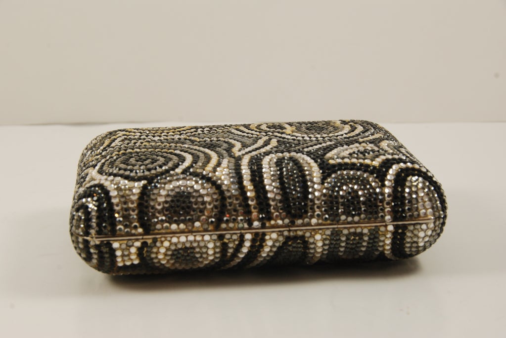 Judith Leiber full bead minaudiere in black, black diamond and clear rhinestones. All stones are present. The clasp is black onyx and works well. Bag closes securely. Lining is silver leather.

There is an optional shoulder chain that folds into