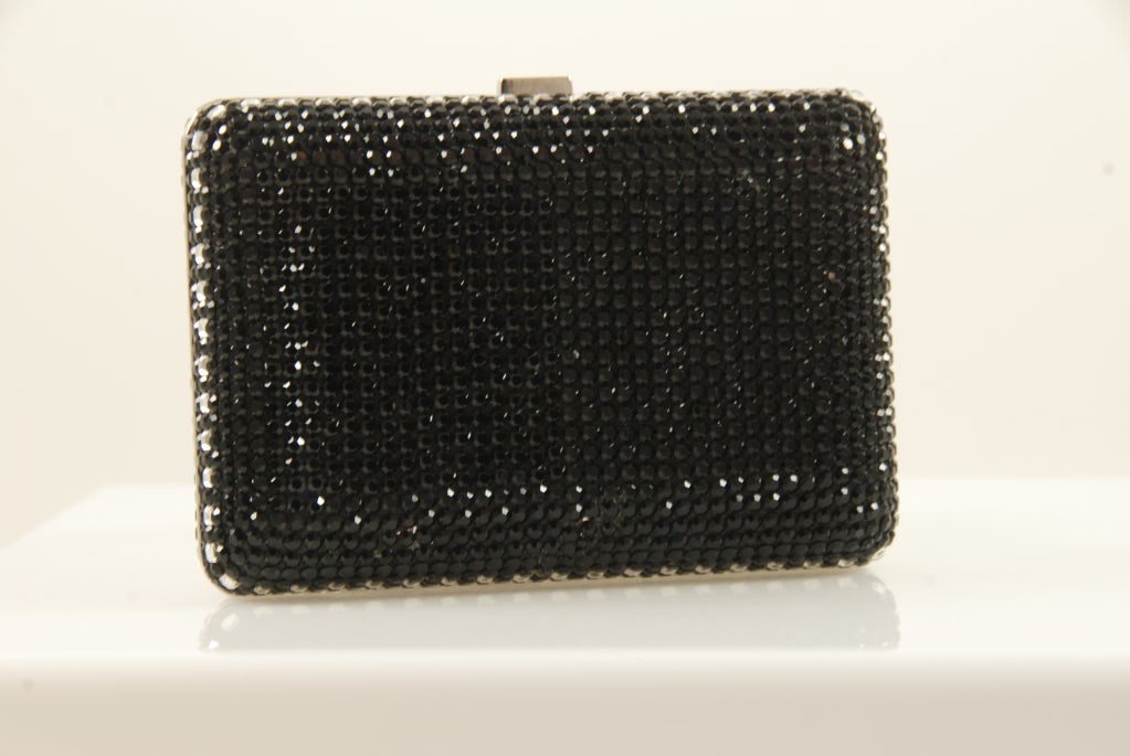 Judith Leiber black and clear rhinestone minaudiere. Front of bag has looks like it has an image of a martini glass or it could be a geometric design. Either ways its gorgeous and the ultimate decision is yours.

Bag closes tightly with a click