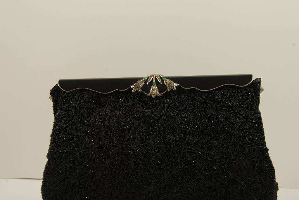 Vintage French black beaded evening bag from the 1940's-1950's. the bead work has an Art Deco style design in all black beads. Some of the beads  glimmer and some have a flat finish. 

The frame of the bag is black enamel with a center design of