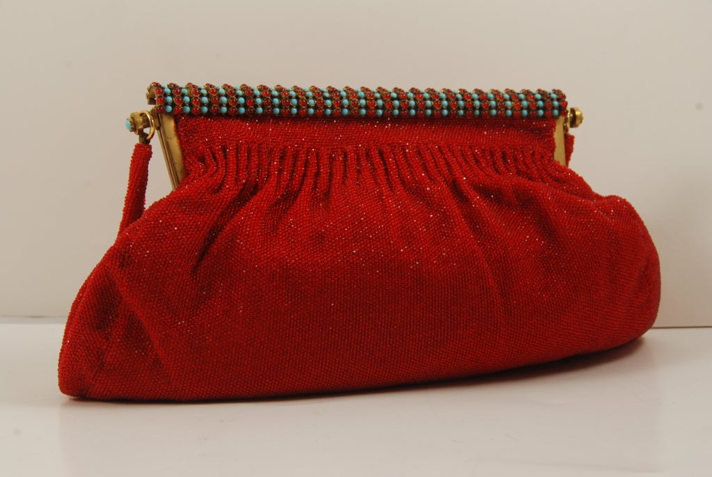 Vibrant red beaded evening bag, made in France circa 1940's. The frame is composed of alternating rows of faux red and turquoise cabochons.

Red beaded strap is 15