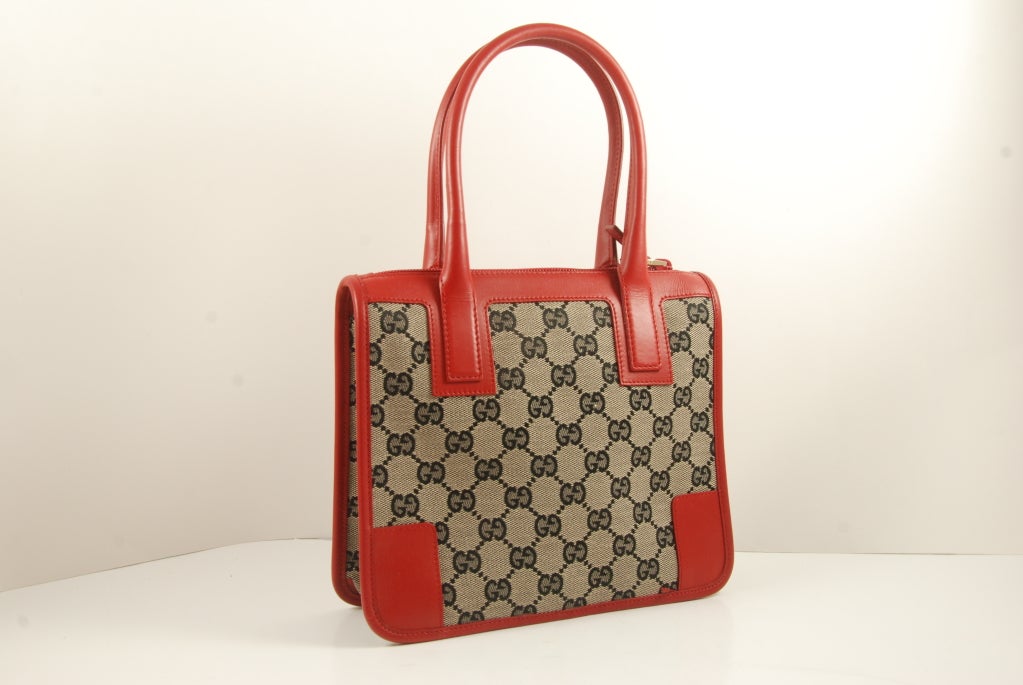 Charming Gucci canvas top handle bag with vibrant red leather trim. Bag opens and closes by a zipper across the top. Zipper works well.


Black lining, feather light, zip compartment.

Straps 5