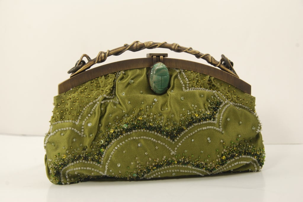 Green satin beaded evening bag by Valentino Garavani. The frame of the bag is a burnished matte gold. The top of the frame resembles a branch entwined by leaves. The clasp is a natural stone that is carved into a scarab. The scarab measures 1.25