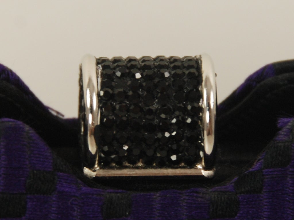 Judith Leiber evening bag from the 1980's with a black rhinestone and chrome clasp. Bag can be used as a clutch or a shoulder bag. The original black satin strap attaches with a toggle so bag can be used as a shoulder bag, The bag also comes with a