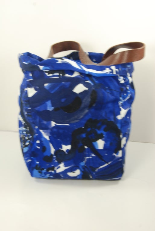Marni tote bag is blue, black and white cotton fabric lined in solid lighter blue knit synthetic fabric. Inside there is one zipper compartment and one slide compartment that will hold a smart phone or something larger. Handles are brown leather and