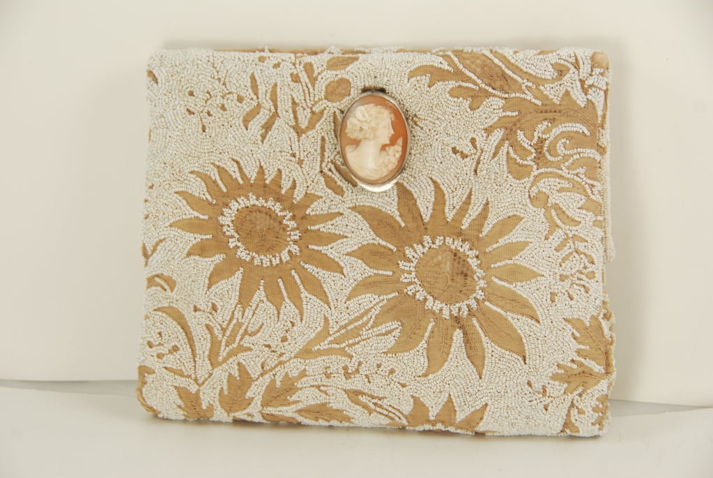 Exquisite clutch evening bag probably made in France in the 1930's or 1940's. White micro beads and sewn over beige lace leaving a floral and leaf design. The clasp is a genuine shell cameo set in silver. The cameo is carved in the classic manor.