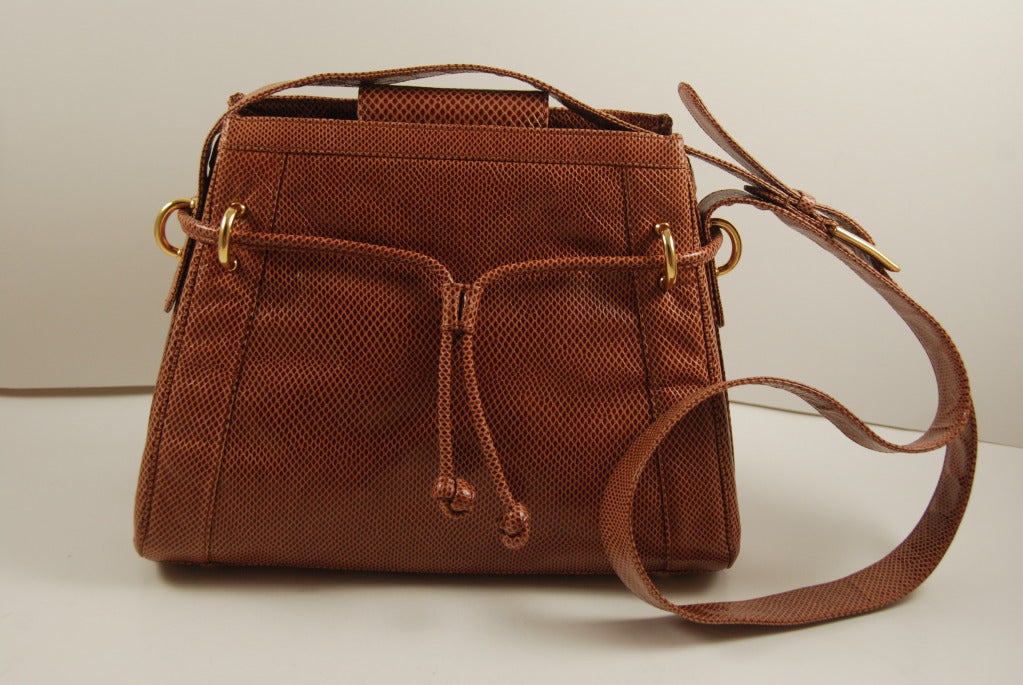 Judith Leiber mocha colored karung (lizard) day/night bag. The bag closes by a magnetic snap that closes on the inside. There is also the outside lariat strap that opens and closes with a karung slide. An interesting detail is the buckle on the