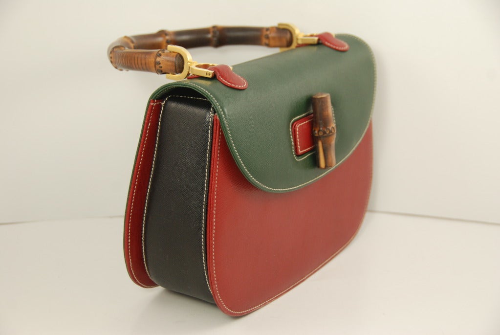 Multi colored leather bag with a bamboo handle and turn lock that is both fun and classic at the same time.The front flap and rear of the bag is a deep green, the front of the bag is red and the gussets are red.The bottom and sides of the bag are