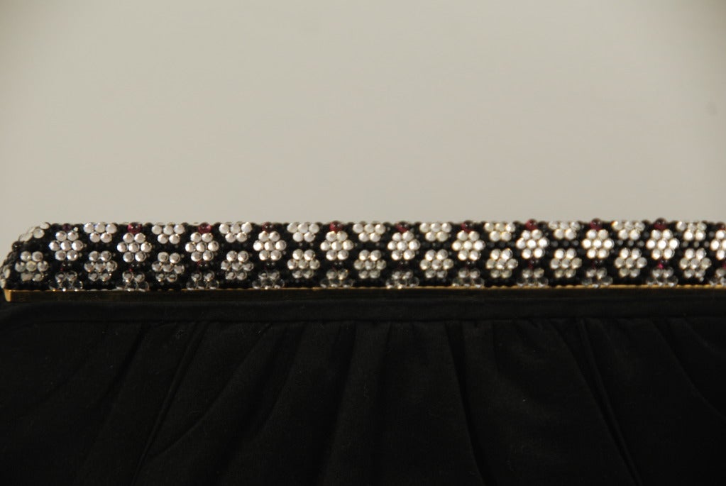 Judith Leibe rblack satin evening bag with rhinestone frame from the 1980s. The stunning rhinestone frame is done in a black and white honeycomb pattern and is accented with garnet cabochon stones. The frame acts as the clasp, it is on a spring