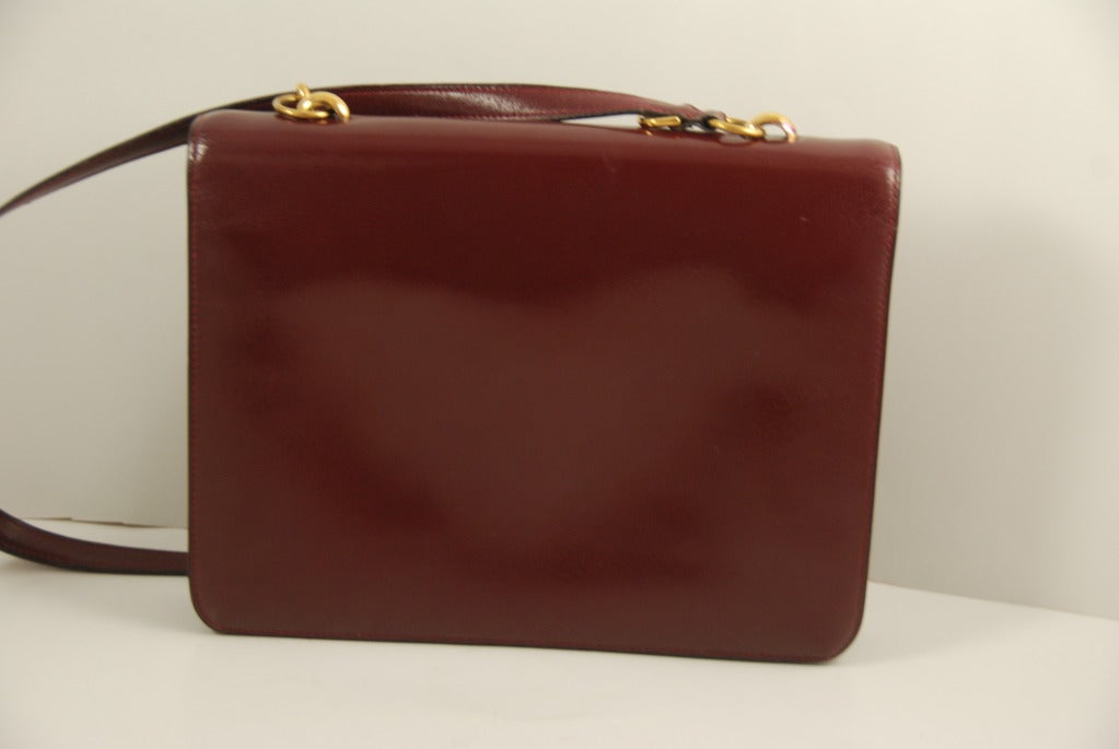 Vintage Hermes oxblood leather bag from the 1960s. Bag opens and closes by a leather tab that slips into a bass buckle. The strap is adjustable so the bag can be worn over the shoulder or carried as a handbag. To shorten the strap you double it up