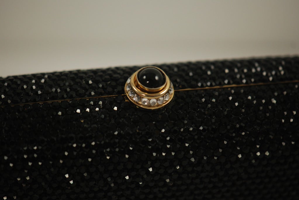 It is amazing how a minaudiere entirely encrusted with rhinestones can be so simple and yet elegant. The bag is entirely covered with black jet rhinestones except for the two lines of clear rhinestones that intersect towards the side of the purse.