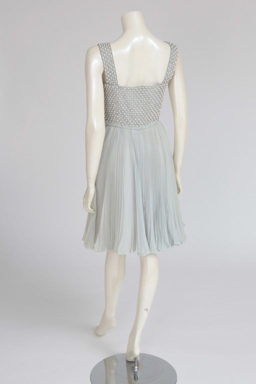 Charming eau de nil chiffon cocktail dress from Nina Ricci (circa 1960). The bodice is entirely covered with a shimmer of iridescent crystals (rhinestone) and silver embroidery. Graceful pleated sun skirt and zip closure on the left side.

Fits