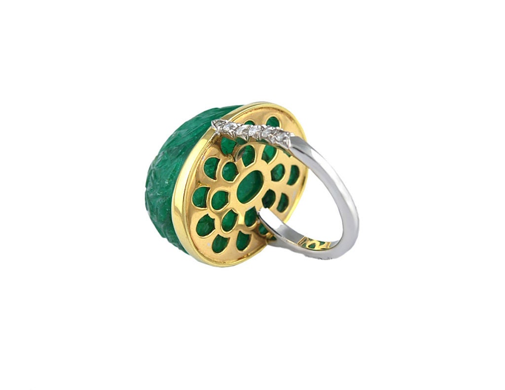 A remarkable carved Moghul cabochon emerald embellished with a dew drop rose cut diamond set in a gold bezel set mount and diamond set band.