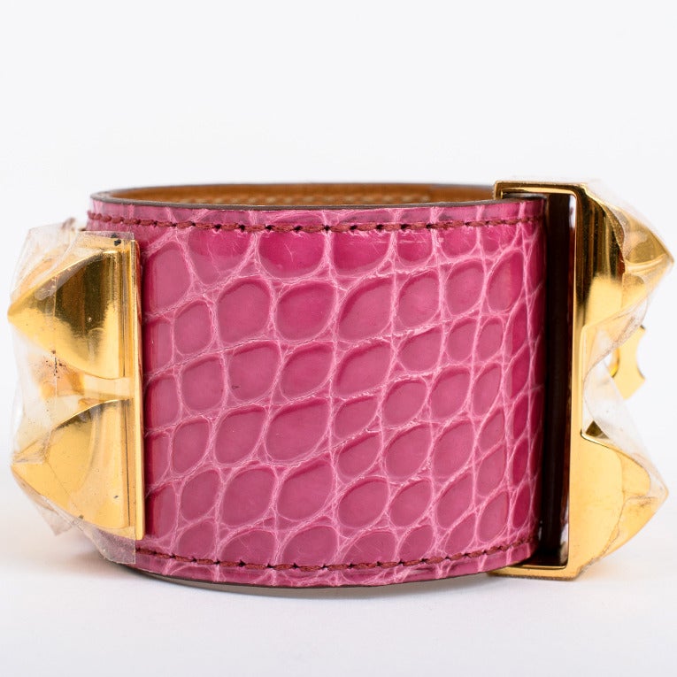 Hermes Collier de Chien (CDC) Fuchsia alligator skin bracelet cuff size Small with gold plated pyramid studs and ring and adjustable push lock closure.

Collection: P in a square (2012)

Condition: Pristine; store fresh condition

Accompanied
