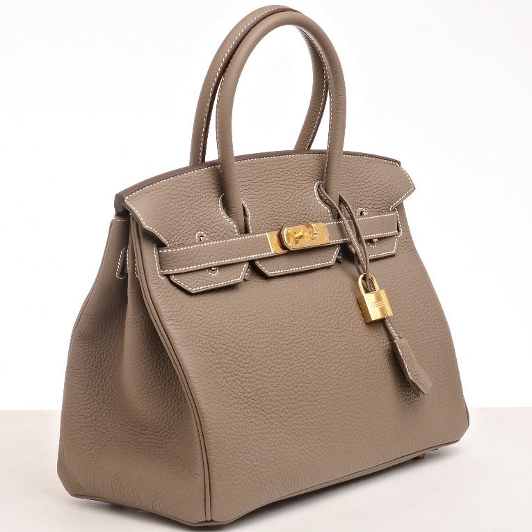 Hermes Etoupe togo leather Birkin 30cm with white contrast stitching, gold hardware, front toggle closure, and clochette with lock and two keys, double rolled handles, Etoupe chevre liing with one zip pocket with Hermes engraved pull and open pocket