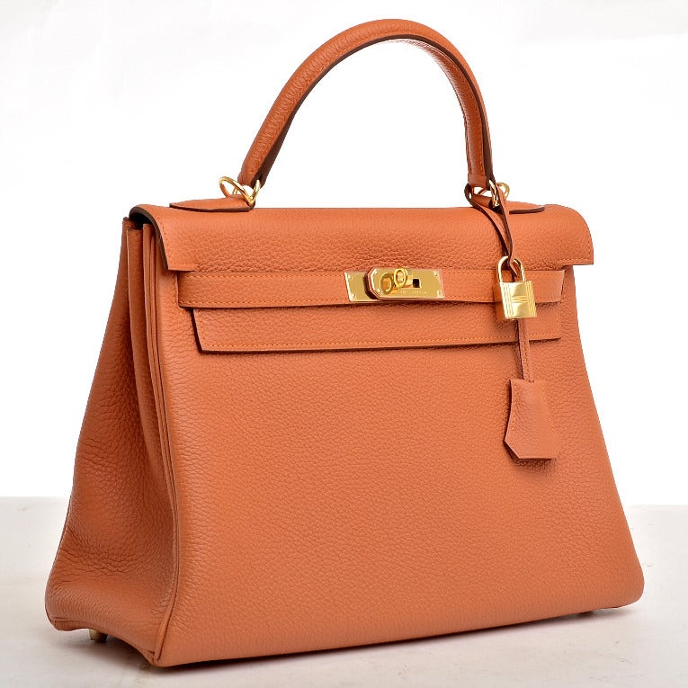 Hermes Orange H togo leather Kelly 32cm with tonal stitching, gold hardware, front toggle closure, clochette with lock and 2 keys, single rolled handle, removable shoulder strap and Orange H chevre lining with one zip pocket with Hermes engraved