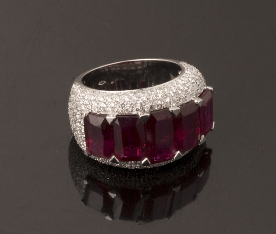 A gorgeous ruby and diamond ring featuring five emerald-cut Thai rubies totaling 10.37 carats and set in 18 karat white gold.  The ring is accented with 1.90 carats of pave-set, round brilliant cut diamonds.  The ring is a size 6 and can be resized.
