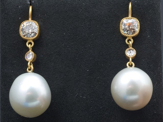 A fabulous pair of earrings featuring two matching South Sea, white pearls measuring 16 millimeters.  The pearls dangle from one Old Mine cut, cushion shaped, brownish-pink diamond and one rose cut, round shaped diamond on each ear.  The diamonds