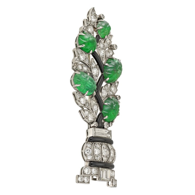 A French Art Deco diamond and carved emerald brooch in the form of a stylised bay tree, comprising openwork diamond set foliage, claw-set carved emerald flowers, a black enamel stem and an openwork planter set with brilliant and baguette cut