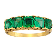 Anello vittoriano con smeraldo e cinque pietre intagliate in oro a forma di mezzo cerchio
