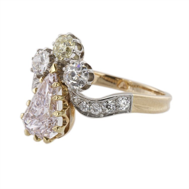 A turn-of-the-century pink and white diamond ring, the natural fancy pink pear-shaped diamond weighing 1.43 carats (HRD Report ), set within two white and one yellow brilliant-cut diamonds, the platinum and yellow gold mount with diamond-set