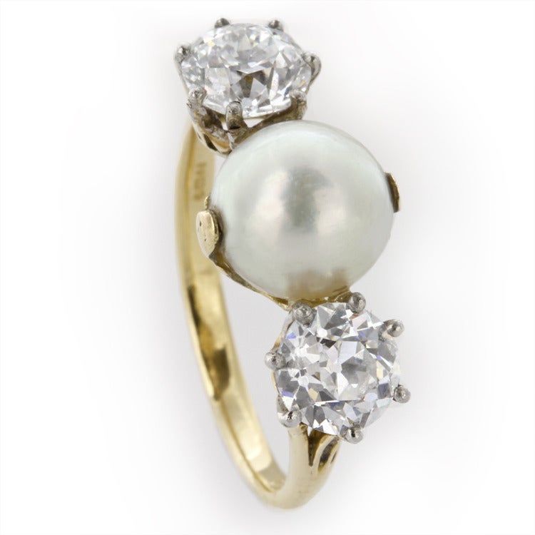 A late Victorian natural pearl and diamond ring, the natural pearl weighing 3.15 carats, measuring approximately 8mm in diameter, an old-cut diamond set to either side, weighing 0.79 and 0.77 carats, of D colour, SI1 clarity, silver claw-set to a